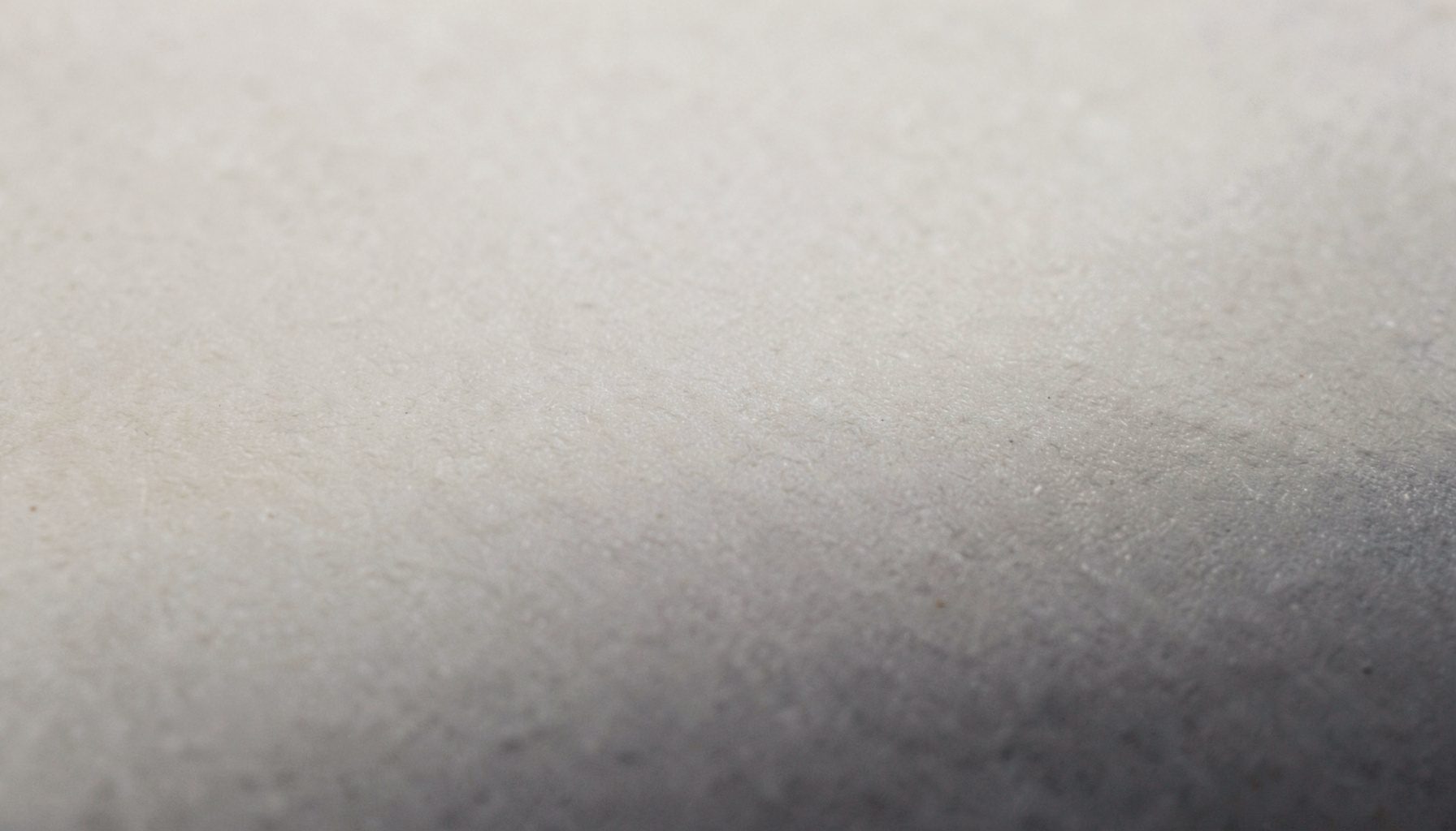 A wide atmospheric photograph of a calm, neutral-toned abstract surface with soft beige and charcoal gradients, quiet and professional