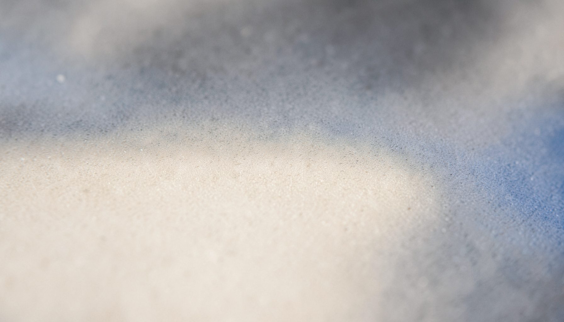 A wide atmospheric photograph of a calm, neutral-toned abstract surface with soft beige and charcoal gradients, quiet and minimal